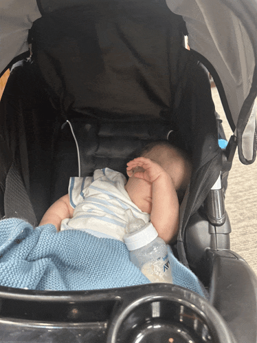 a baby sleeping in a stroller with a bottle that says ' avent ' on it