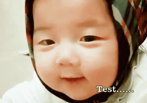 a baby wearing a head scarf is smiling and says test on the bottom right