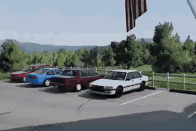 a white car is parked in a parking lot next to a red car and a blue car