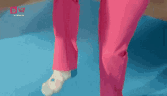a woman in pink pants is standing on a blue mat