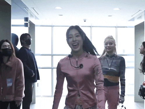 a woman in a pink shirt is laughing in a hallway with other women