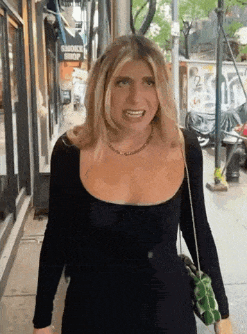 a woman in a black dress is walking down a sidewalk in front of a smoke shop .