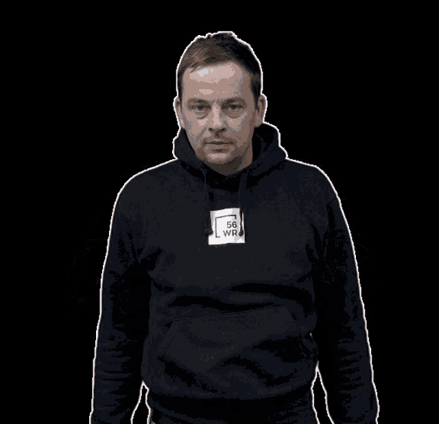 a man wearing a black hoodie with a white square that says sg wr on it