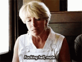 a woman in overalls is sitting in a restaurant and says fucking hell mate .