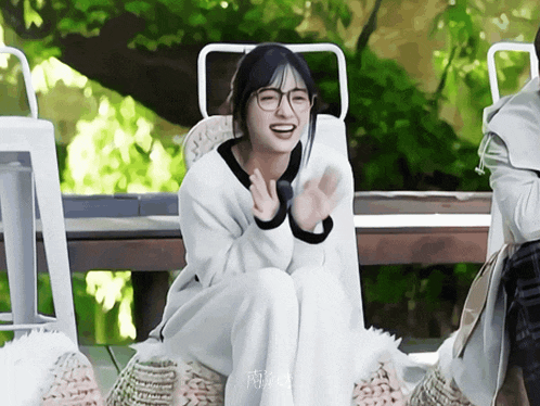 a girl wearing glasses is sitting on a chair
