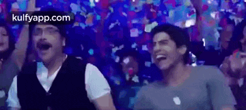 a group of people are dancing in a room with confetti flying around them .