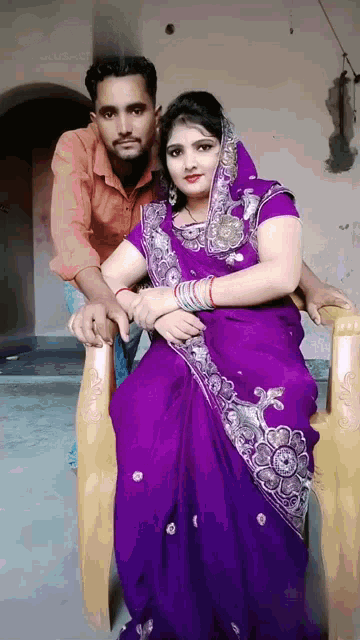 a woman in a purple dress is sitting next to a man