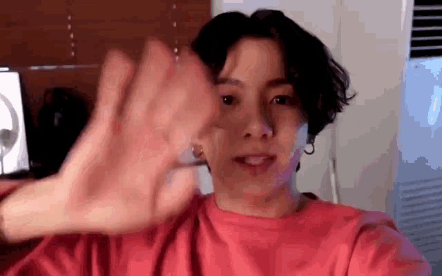 a young man in a red shirt is making a hand gesture .