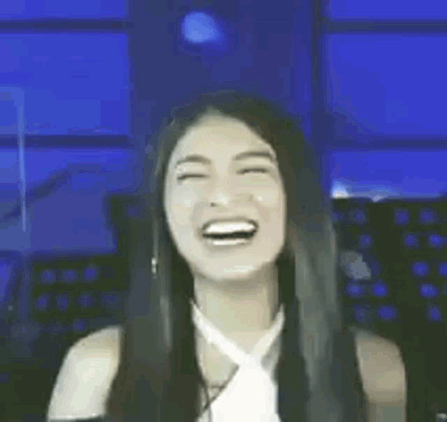 a woman with long black hair is smiling in a dark room .