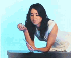 a woman in a white dress is sitting on a table holding a purple object