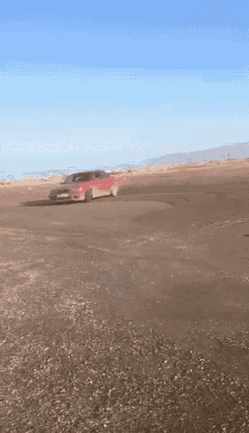 a red car driving on a dirt road with a blue sky in the background