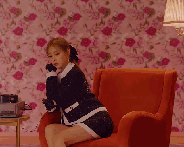 a woman is sitting in a red chair with a clock that says 10:08