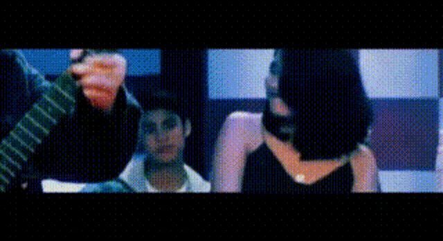 a man is holding a guitar in front of a woman in a black dress