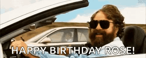 a man with a beard is driving a car with the words `` happy birthday rose '' written on it .
