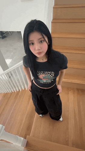 a girl wearing a california shirt is standing on stairs