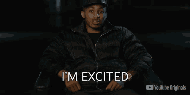 a man is sitting in a chair with the words i 'm excited on the screen