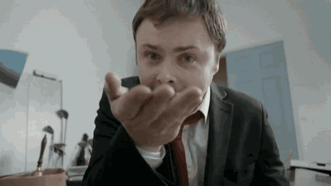 a man in a suit and tie is holding something in his hand and making a funny face .
