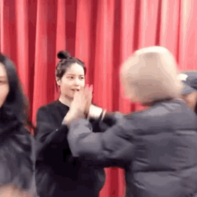 a group of people are standing in front of a red curtain and giving each other high fives .