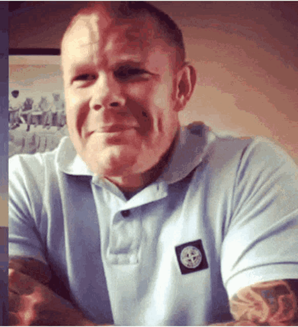a man wearing a light blue shirt with a stone island logo on the front