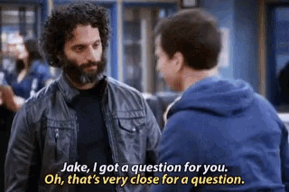 a man with a beard is talking to another man in a room .