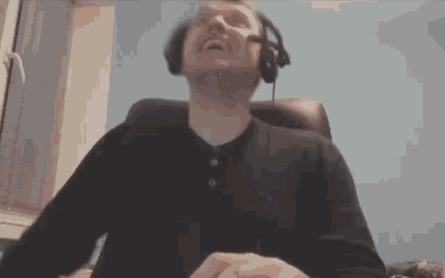 a man wearing headphones is sitting in a chair with his mouth open .