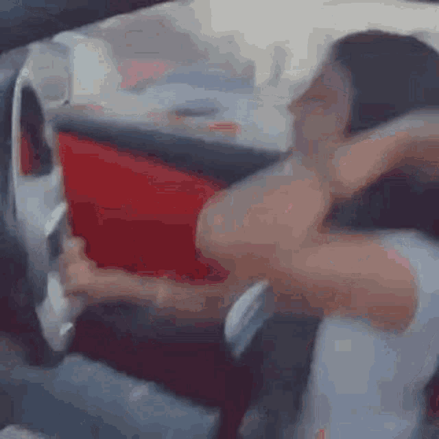 a woman is sitting in the driver 's seat of a car holding a steering wheel .