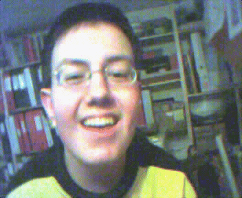 a young man wearing glasses and a yellow shirt smiles