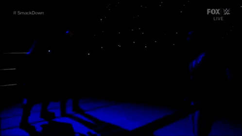 a person is laying on the ground in a dark room with a blue background .
