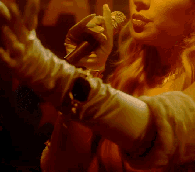 a woman is singing into a microphone while wearing gloves