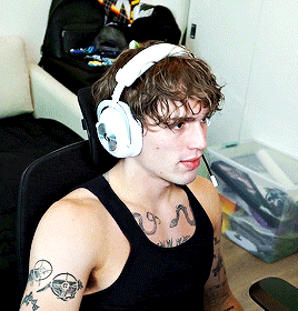 a man wearing headphones and a black tank top with a tattoo on his arm