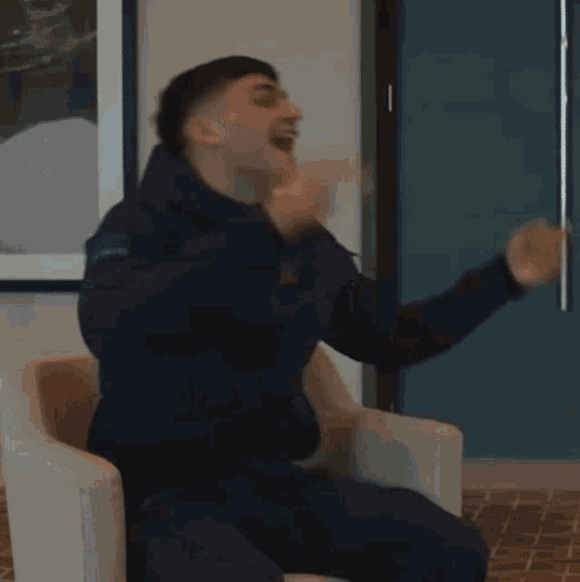 a blurry picture of a man sitting in a chair with the letter o on his jacket