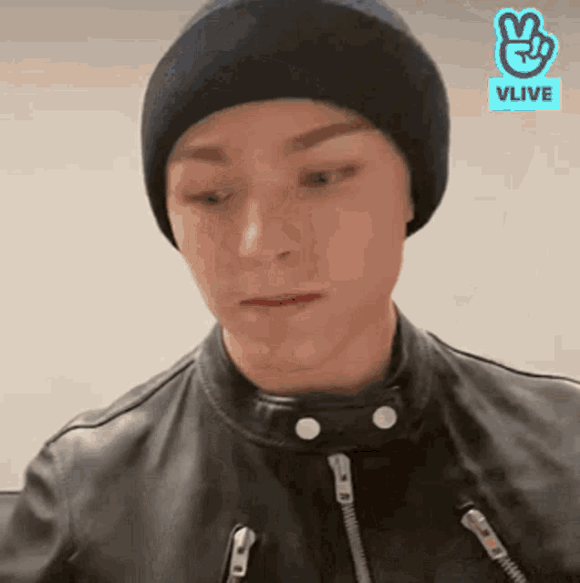 a man wearing a black beanie and a leather jacket is making a face .