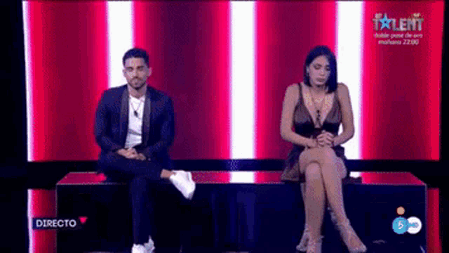 a man and a woman are sitting next to each other on a bench on a television show .