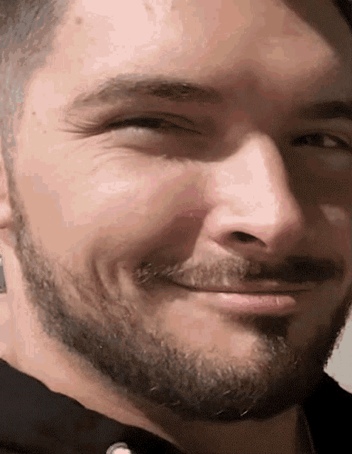 a man with a beard and mustache smiles for the camera