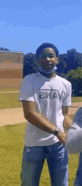 a man wearing a mask and a white t-shirt is standing in a field .