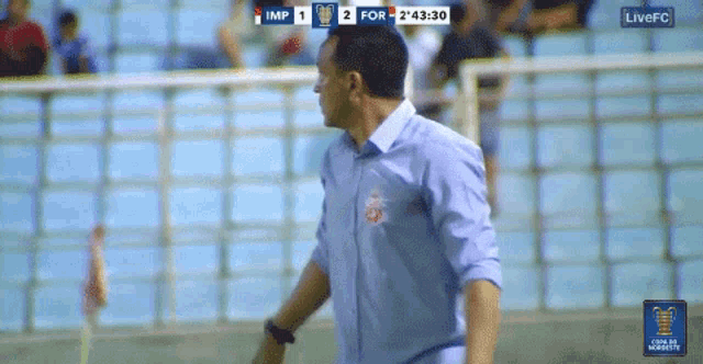 a man stands in front of a scoreboard that says imp 2 for 2