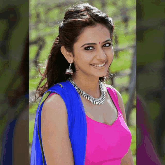 a woman in a pink top and blue jacket is smiling for the camera