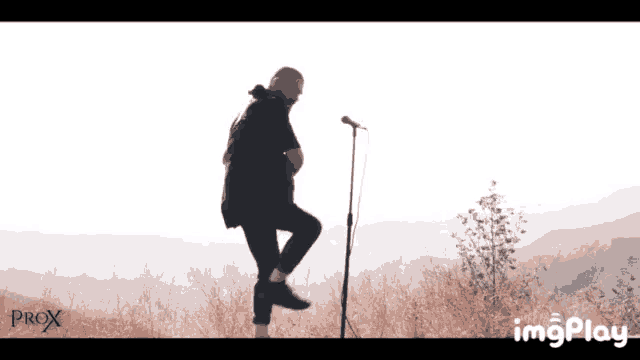 a man is singing into a microphone while standing on one leg ..
