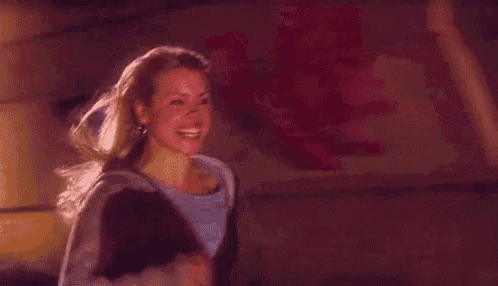 a woman is smiling and looking at the camera in a dark room .