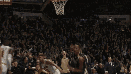 a basketball player is celebrating a basket while a referee watches .