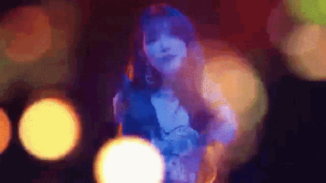 a woman in a blue dress is dancing in a dark room with a lot of lights .