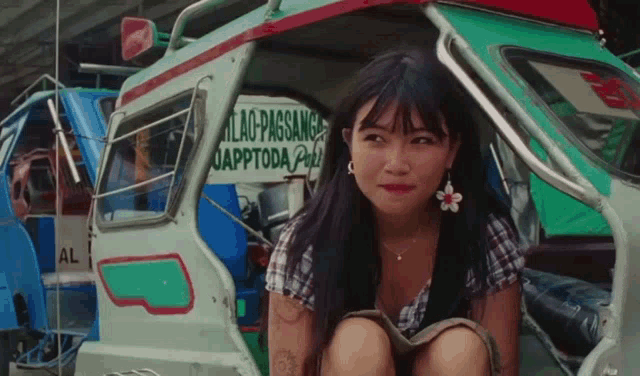 a woman in a plaid shirt is kneeling in front of a sign that says uapptoda