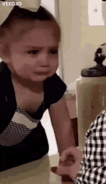 a little girl is crying in front of a mirror while a woman holds her hand .