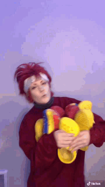 a person with red hair is holding a bunch of yellow crocs .