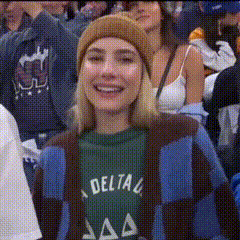 a woman wearing a delta shirt and a beanie is smiling