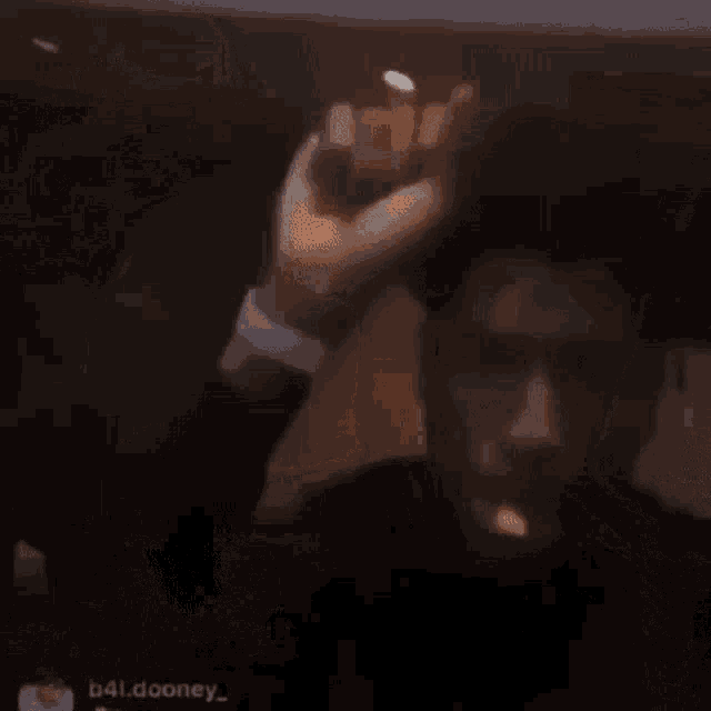 a man is holding his fist up in the air while smoking a cigarette in a dark room .