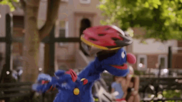 elmo from sesame street is wearing a helmet and roller skates in a park .
