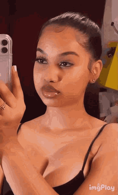 a woman is taking a selfie in front of a mirror with her phone .