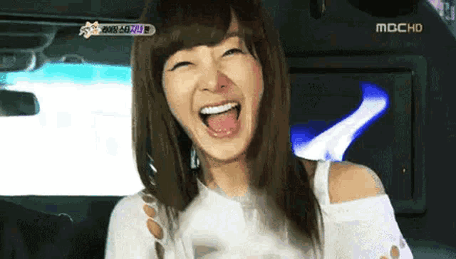 a woman is laughing in a car with her mouth open .