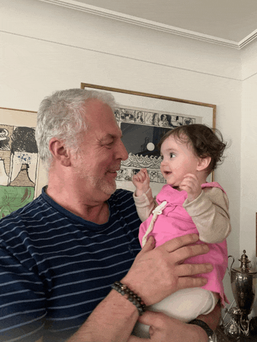 a man in a striped shirt is holding a baby
